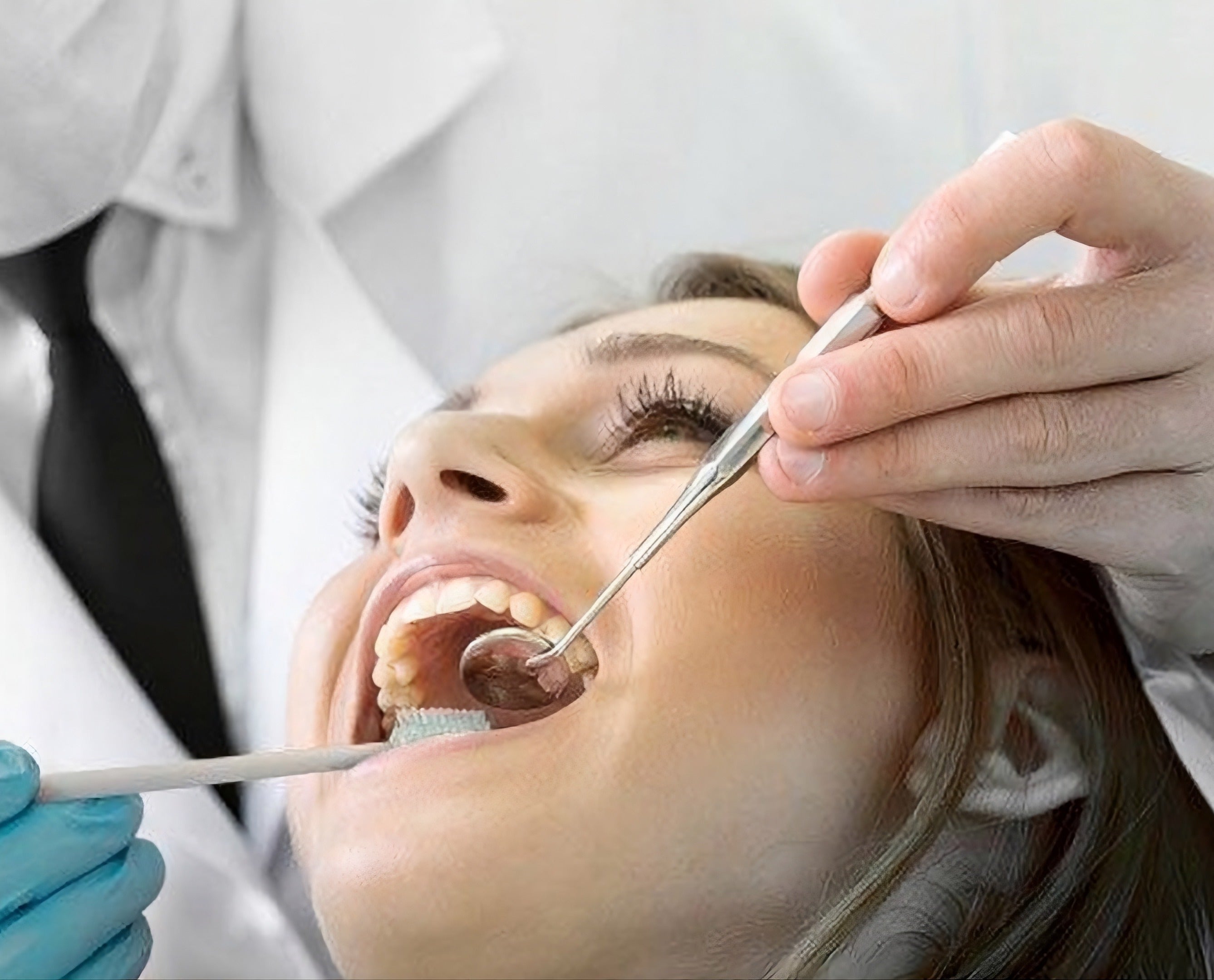 Healthcare professional providing clinical mouth care to a patient using dental instruments in a clinical setting.